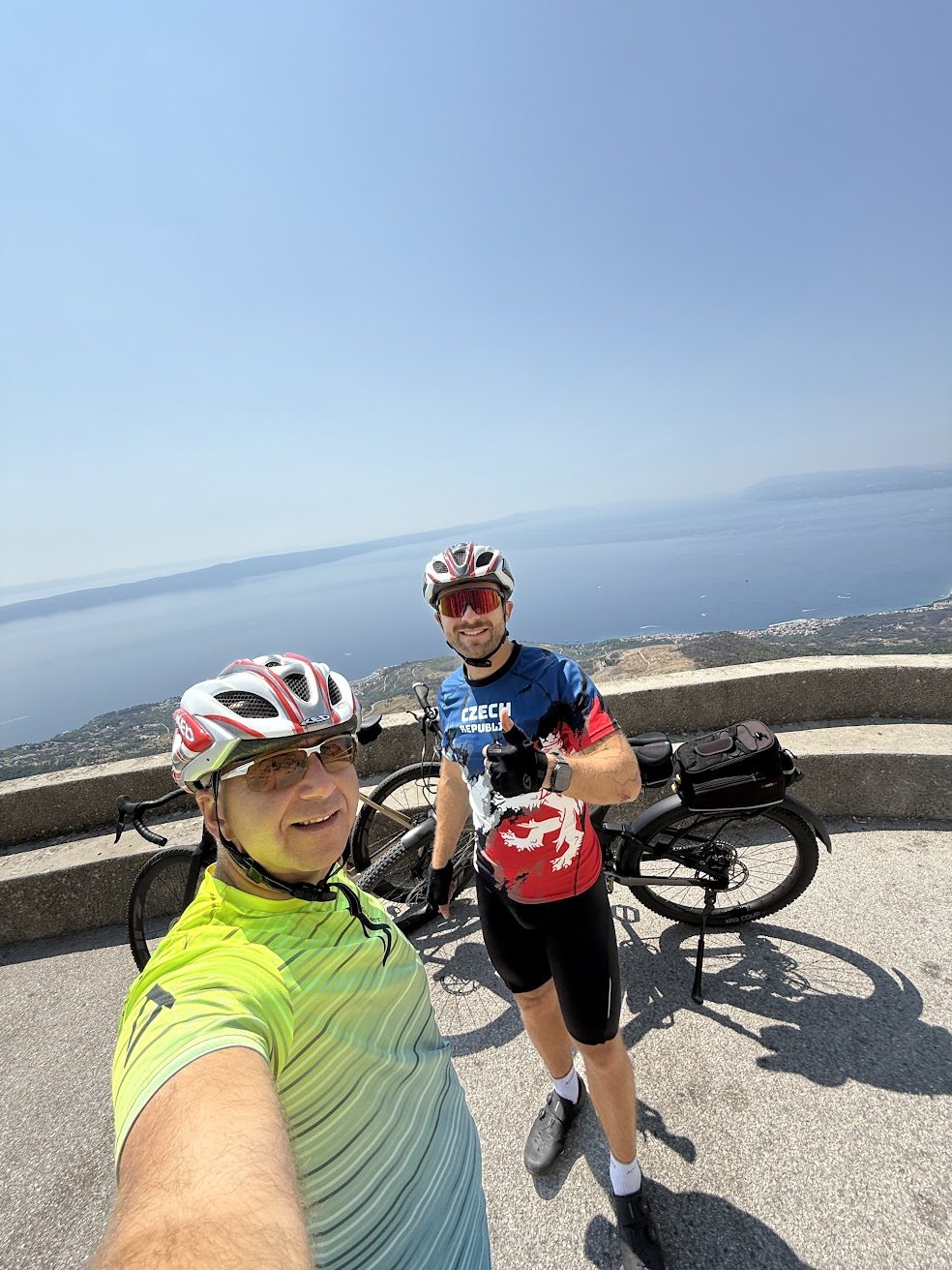 Dva cyklisté s jízdními koly na vyhlídce nad pobřežím