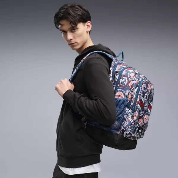  Batoh PUMA ACADEMY AOP BACKPACK 09115027 MIDNIGHT PETROL/FOR ALL TIME RED/RUNNING BADGES AOP 